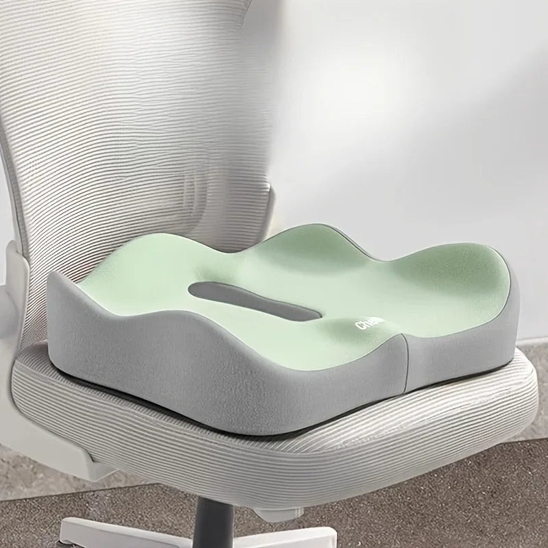 Green memory foam seat cushion with tailbone cut-out on an office chair